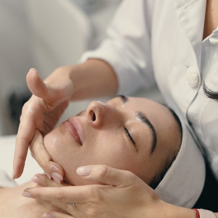 young-woman-lies-with-closed-eyes-cosmetologist-making-procedure-scaled.jpg